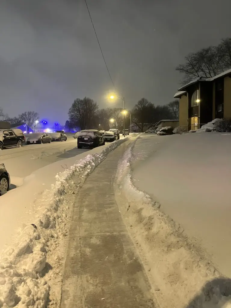 Cleared sidewalk through deep snow at night